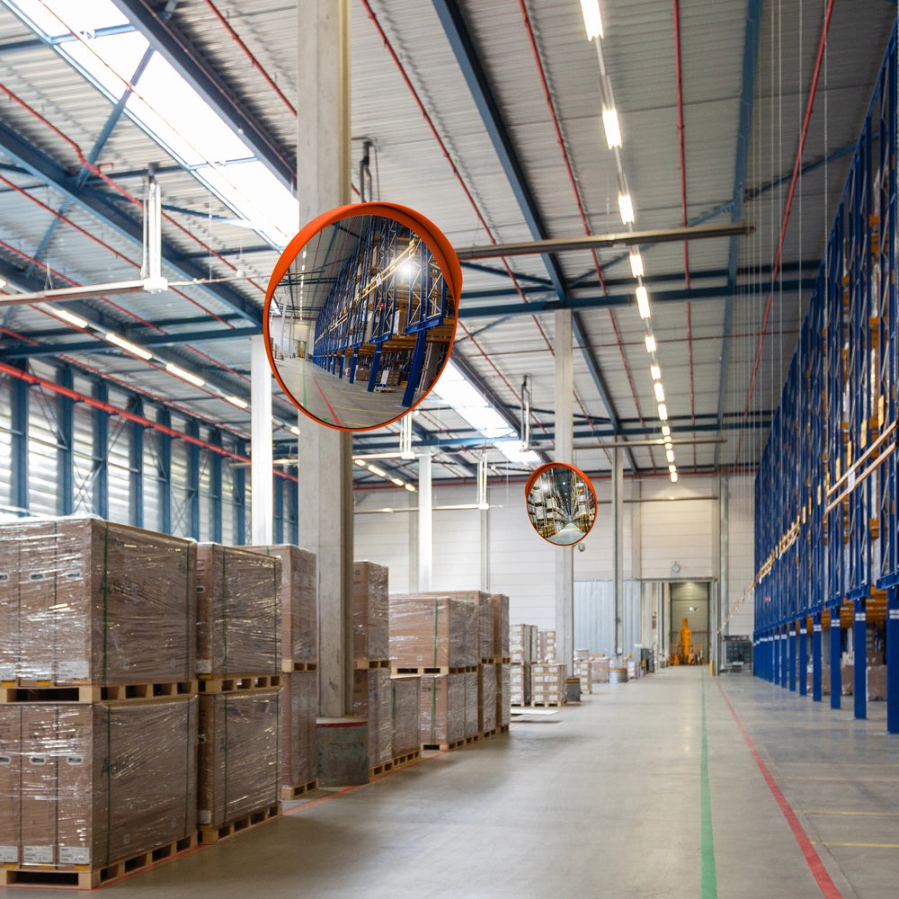 Large warehouse with stacked pallets and large mirrors on the ceiling.