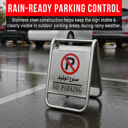 A stainless steel A-frame 'NO PARKING' sign with a red and black 'P' symbol and Arabic text, placed on a wet asphalt parking lot 